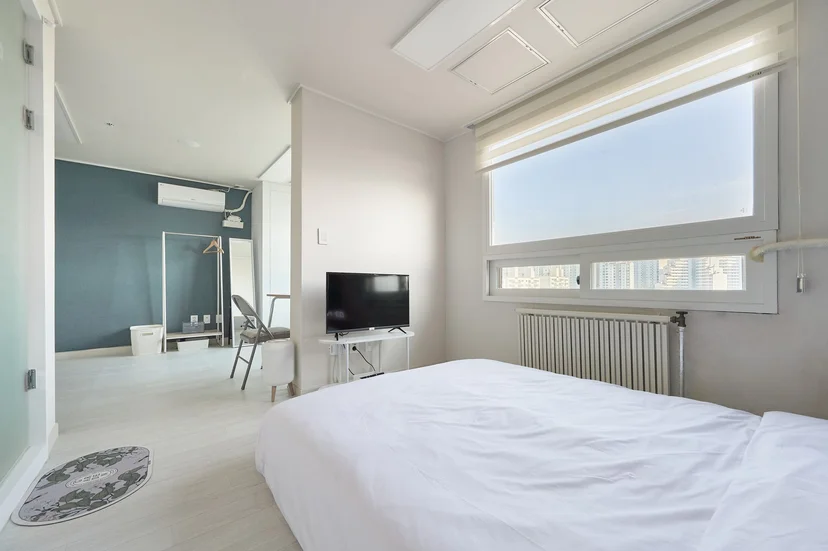 White bed facing a wide window with the living area behind (Listing ID : 32541)
