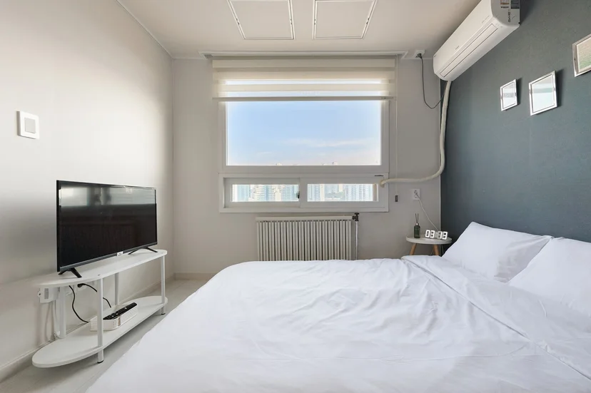 Bedroom with TV stand and a large window over the city (Listing ID : 32541)