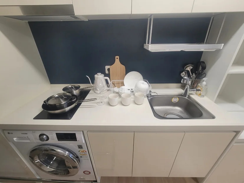 Bright kitchenette with induction cooktop, sink, dish rack, kettle, and LG washing machine (Listing ID : 28279)