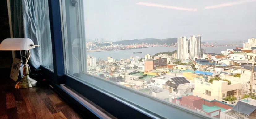 Window view of Busan harbor and rooftops with brass desk lamp (Listing ID : 24807)