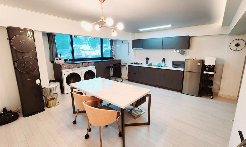 Open-plan living and kitchen with marble dining table, washer-dryer, and ocean-view window (Listing ID : 24807)