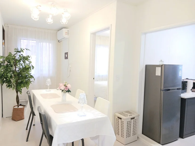 Bright white dining area with a four-seat table and flowers beside the kitchen (Listing ID : 29514)
