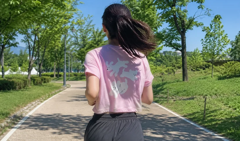 마플 테크이지 기능성 반팔 티셔츠 - 러닝 크루 캐릭터를 인쇄해 제작한 핑크 티셔츠 뒷면을 야외 달리기 중 착용한 이미지