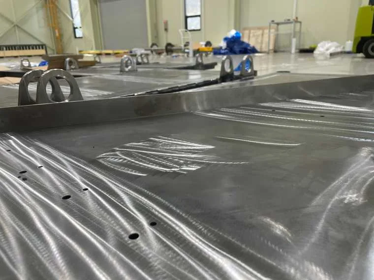 Close-up of CNC machined aluminum battery pack tray showing precision machining marks and lifting brackets