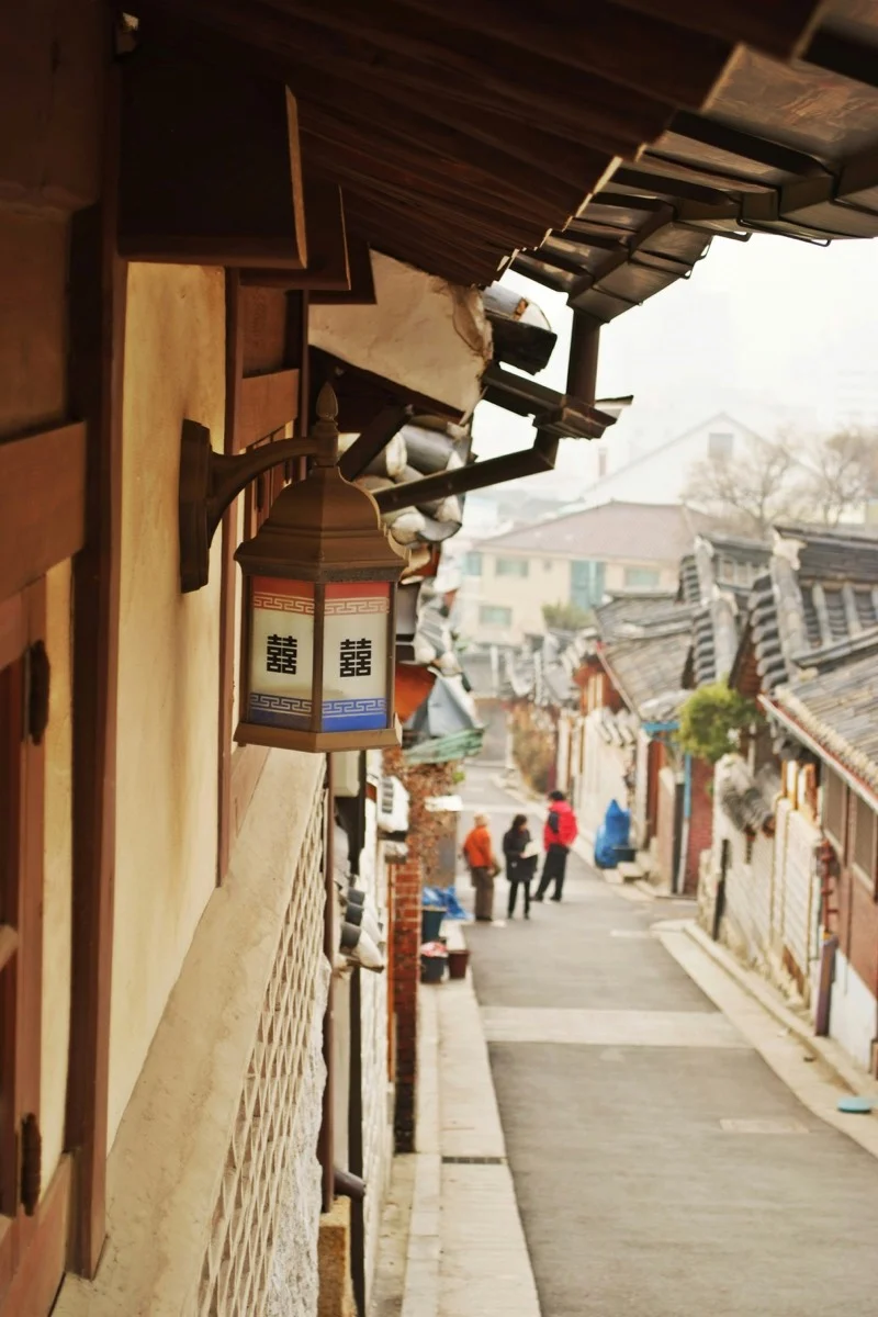Traditional Korean hanok houses in Bukchon Hanok Village, Seoul, with visitors walking between the historic buildings