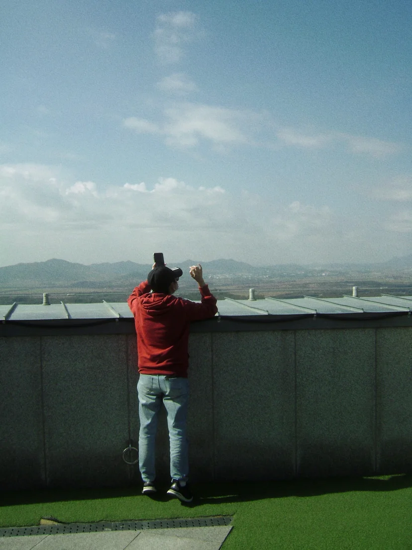 View of the Korean DMZ border area with a figure standing on grass-covered terrain