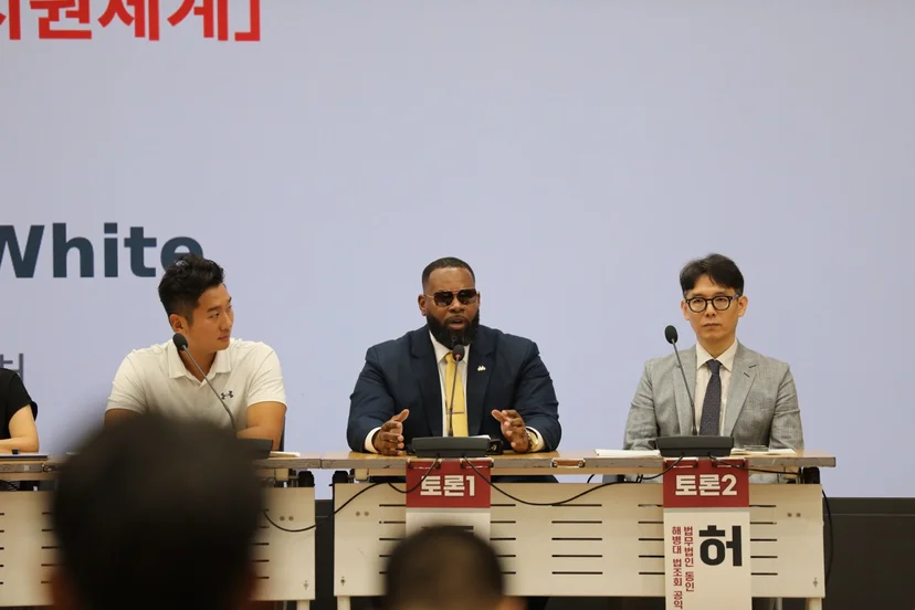 토론 중인 돈타 화이트 — 뒤편 화면에 ‘미국 부상군인 지원체계’ 슬라이드