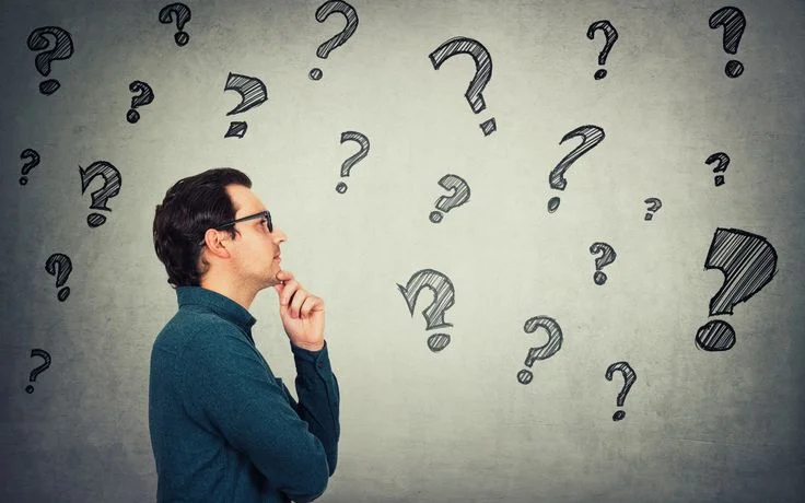 Man surrounded by question marks thinking deeply
