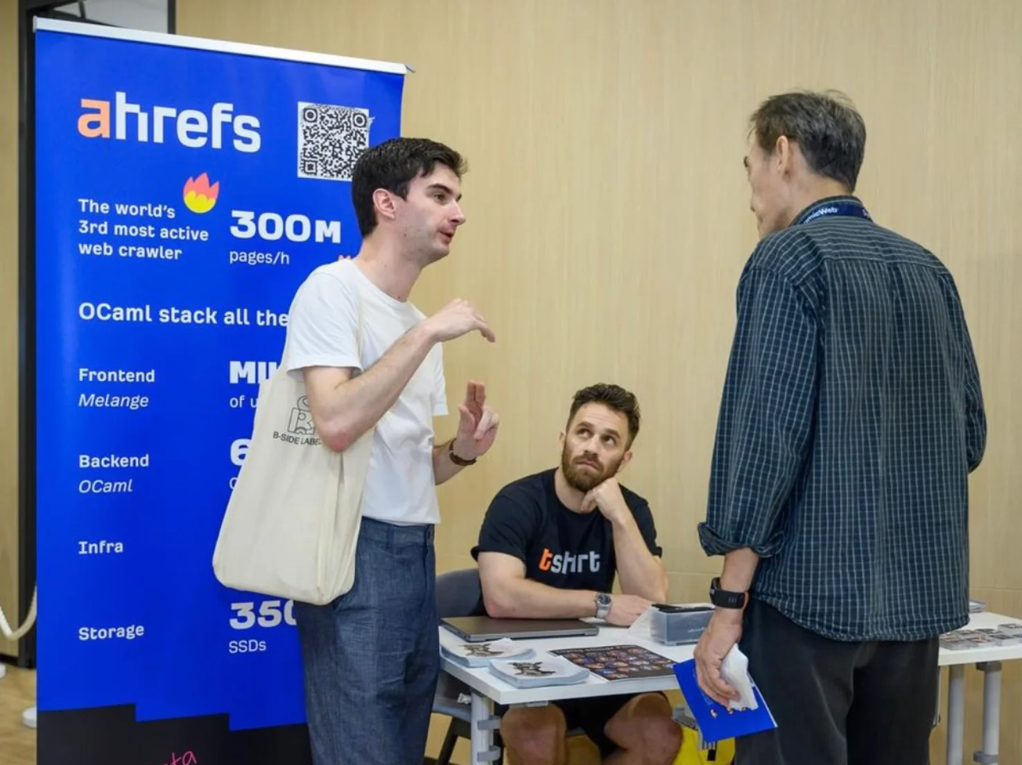 Ahrefs team speaking with visitors at a booth showcasing their web crawler stats