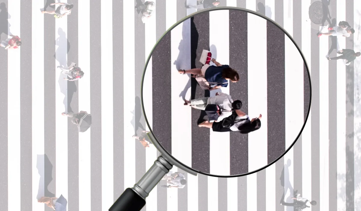 횡단보도를 건너는 사람들 중 일부를 돋보기로 확대해 보여주는 이미지. 팔로워 수가 아닌 타깃 맞춤 인플루언서를 정밀하게 선별하는 과정을 상징적으로 표현