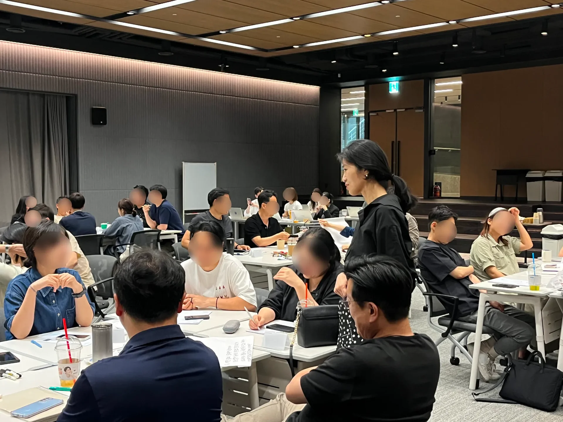 문우리 대표가 토의 중인 테이블 옆에 서서 흐뭇하게 웃으며 대화 내용을 듣고 있다.