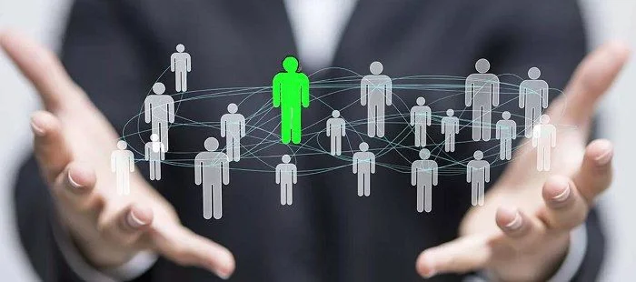 Person holding a digital network of connected people icons with one highlighted in green, representing lead targeting or audience segmentation