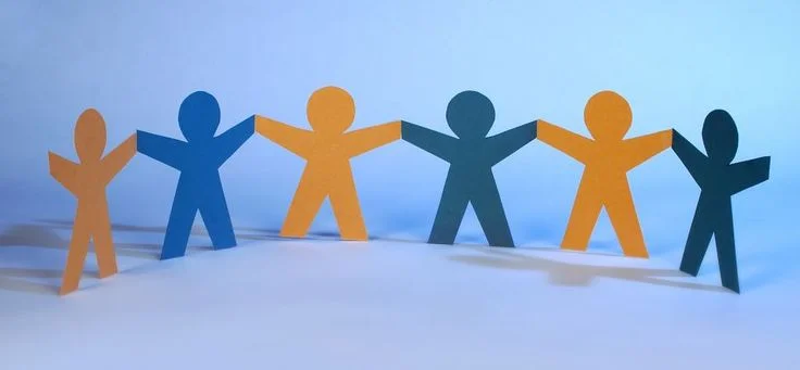 Paper cutout figures in alternating blue and orange colors holding hands in a line, symbolizing community