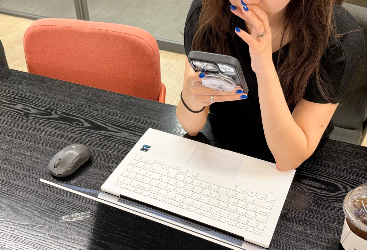 노트북 앞에서 스마트폰을 들여다보는 여성