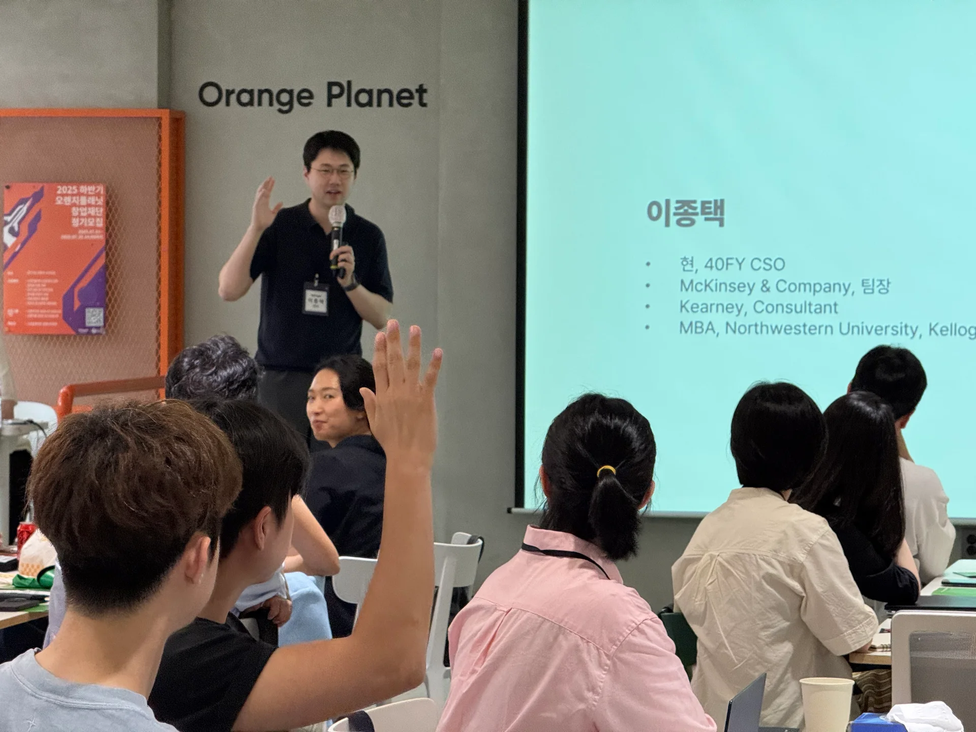 40FY 이종택 CSO가 강연을 시작하며 청중에게 질문을 던지고 있고, 청중 중 한 명이 손을 들어 질문에 응하고 있다.