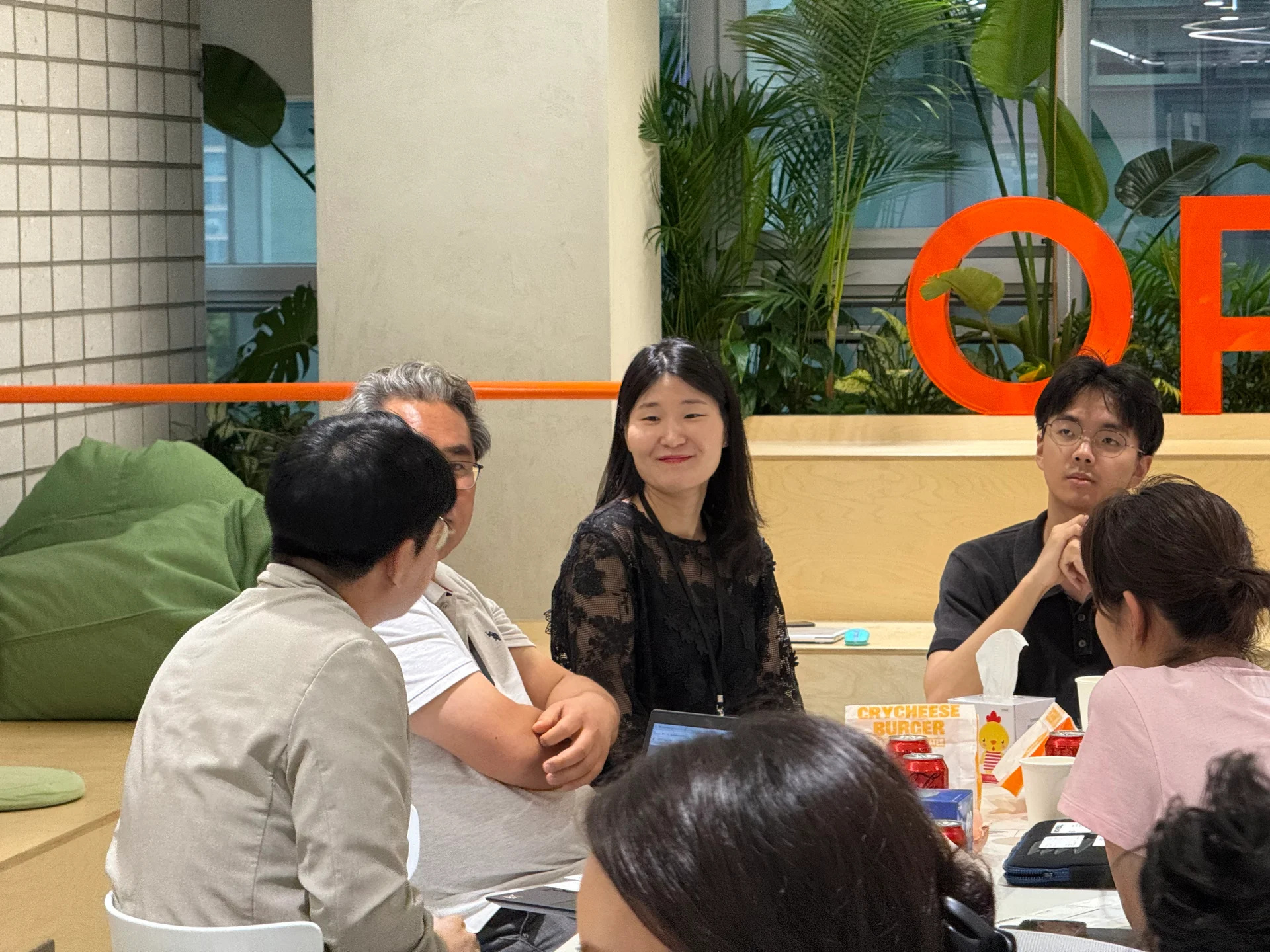 라운드 테이블 세션에서 리더들이 모여 열띤 토의를 벌이고 있고, 해당 조의 담당 코치인 이아람 코치님이 환하게 웃으며 이야기를 듣고 있다.