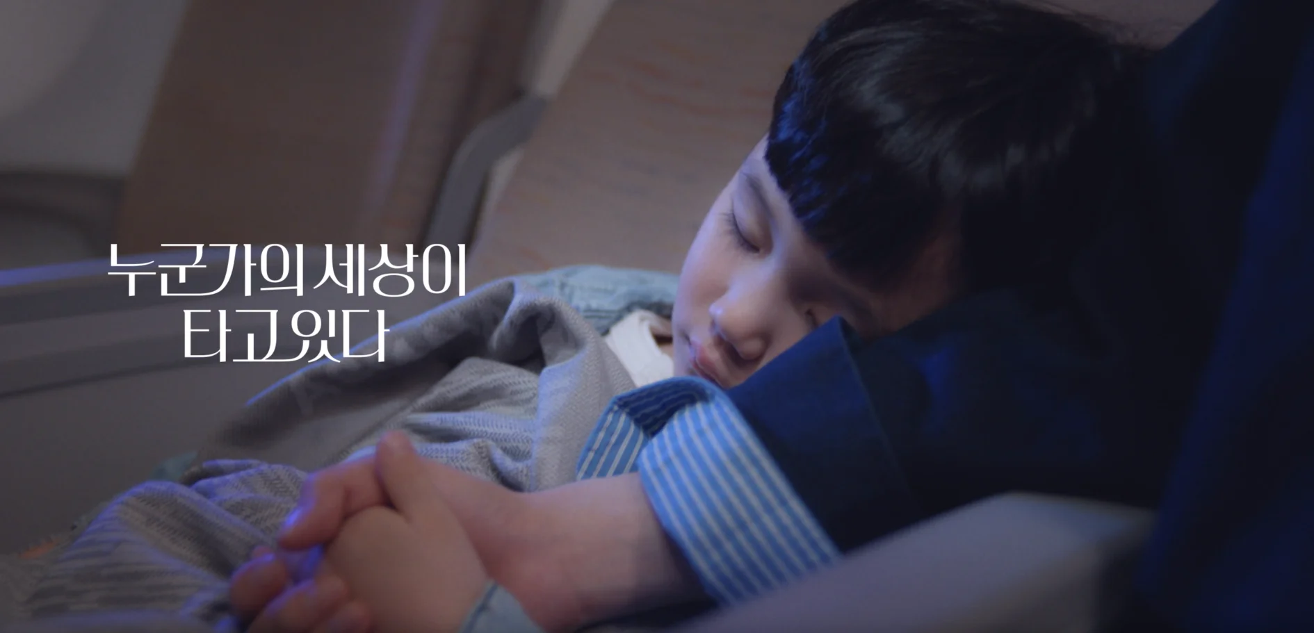 비행기 안에서 아이가 엄마 팔에 기대서 자고 있고, '누군가의 세상이 타고있다'라는 문구가 표시됨