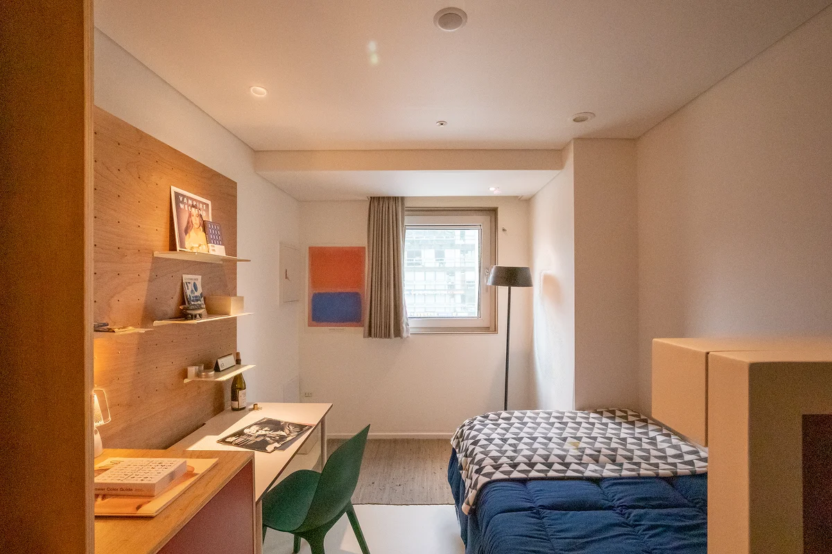 서울 맹그로브 신설 Stay Single 객실 내부 전경. 싱글 침대와 책상, 의자, 수납 선반이 갖춰진 원룸형 개인 공간으로, 장기 숙박과 1인 생활에 최적화되어 있다. 따뜻한 조명과 모던한 인테리어로 편안한 휴식과 집중이 가능한 코리빙 하우스 개인 객실.