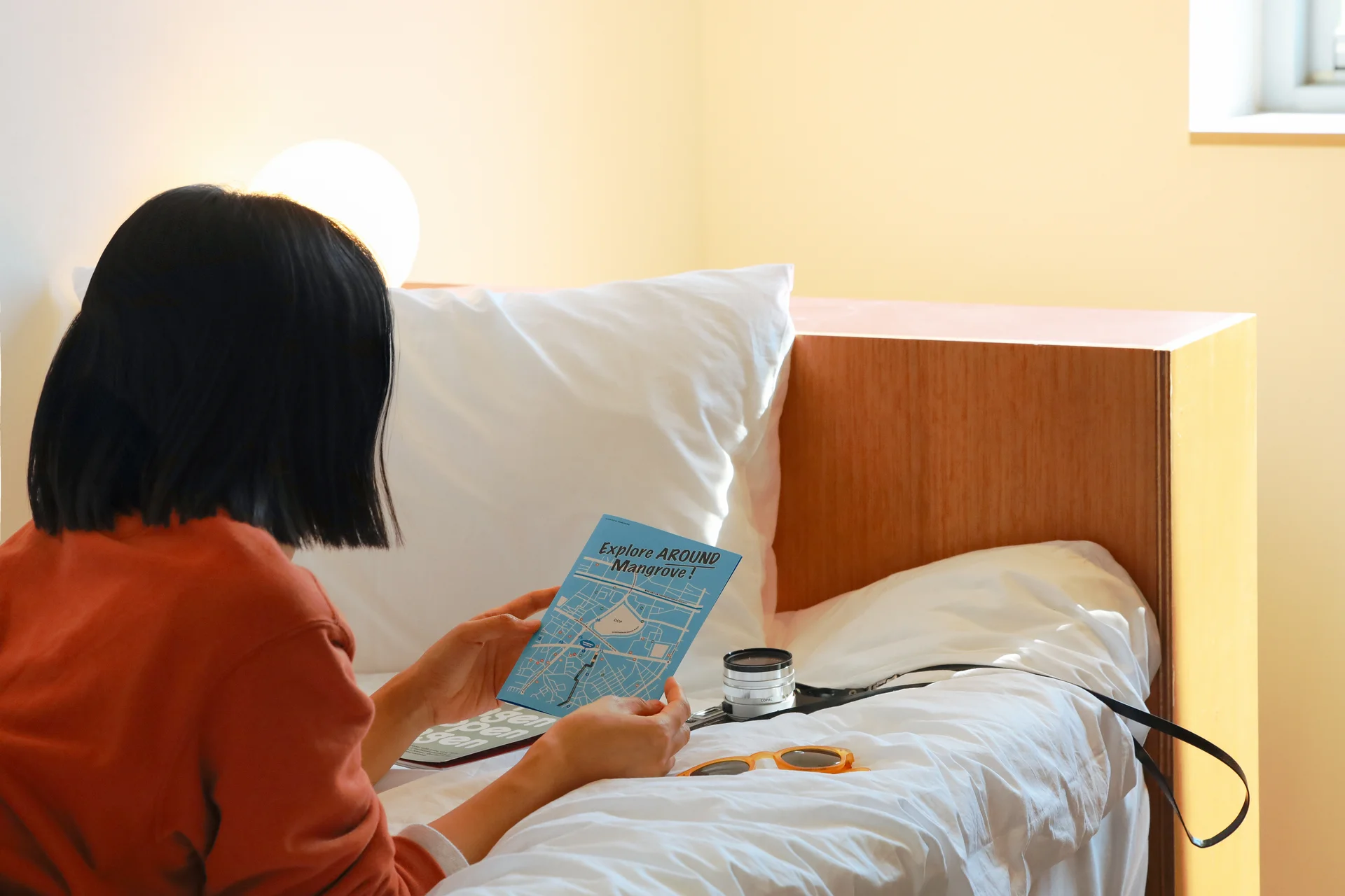 서울 맹그로브 신설 싱글룸 개인 공간. 입주민이 침대에 앉아 책자를 읽는 모습으로, 따뜻한 조명과 심플한 원목 가구가 배치된 원룸형 객실. 장기 숙박과 1인 생활에 적합한 코리빙 하우스 개인 공간으로 편안한 휴식과 자기 개발이 가능한 프라이빗한 환경을 제공한다.