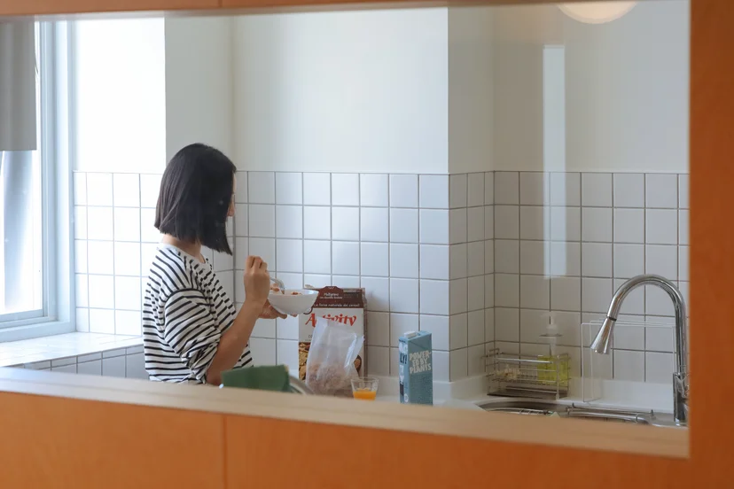 서울 맹그로브 동대문 코리빙 하우스 공용 키친. 입주민이 시리얼과 우유로 아침 식사를 준비하는 모습으로, 싱크대와 조리 공간, 수납장이 갖춰져 있어 장기 숙박과 공동생활에 편리하다. 밝은 채광과 모던한 인테리어로 입주민들이 요리와 식사를 공유할 수 있는 커뮤니티 주방 공간.