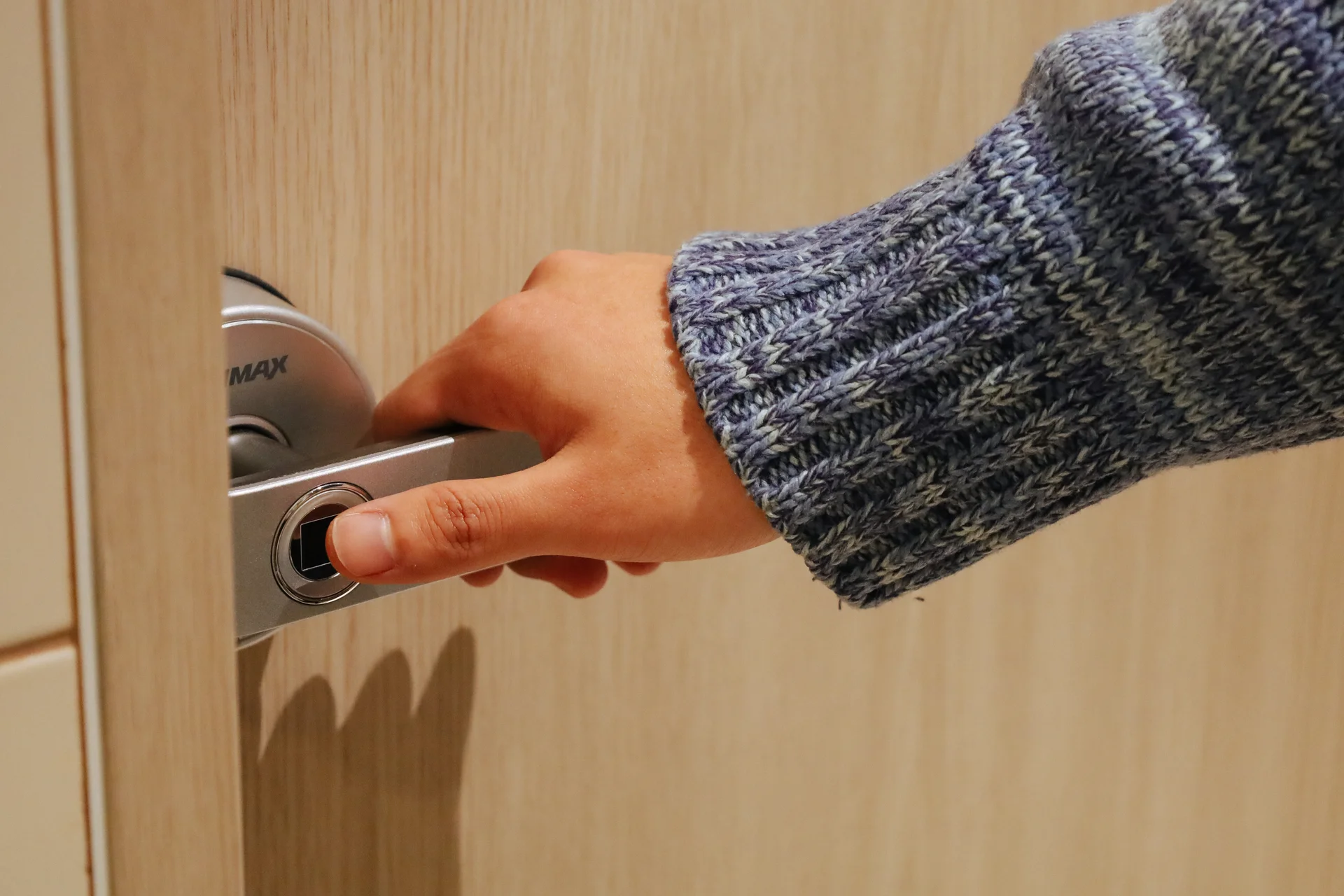 맹그로브 신촌 객실 출입문 도어락을 잡고 있는 손. 장기 숙박 고객이 안심할 수 있도록 지문 인식 방식의 스마트 도어락이 설치되어 있으며, 개인 보안과 프라이버시를 보장하는 안전한 객실 출입 시스템을 보여준다.