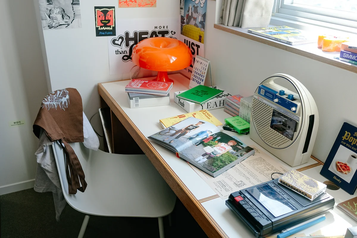 맹그로브 동대문 장기 숙박 Bunk 객실 업무 공간 – 창가에 위치한 책상과 의자, 조명, 잡지와 소품이 어우러진 아늑한 코리빙 워크스페이스. 장기 체류 고객이 공부, 업무, 워케이션을 편리하게 할 수 있는 맞춤형 공간.