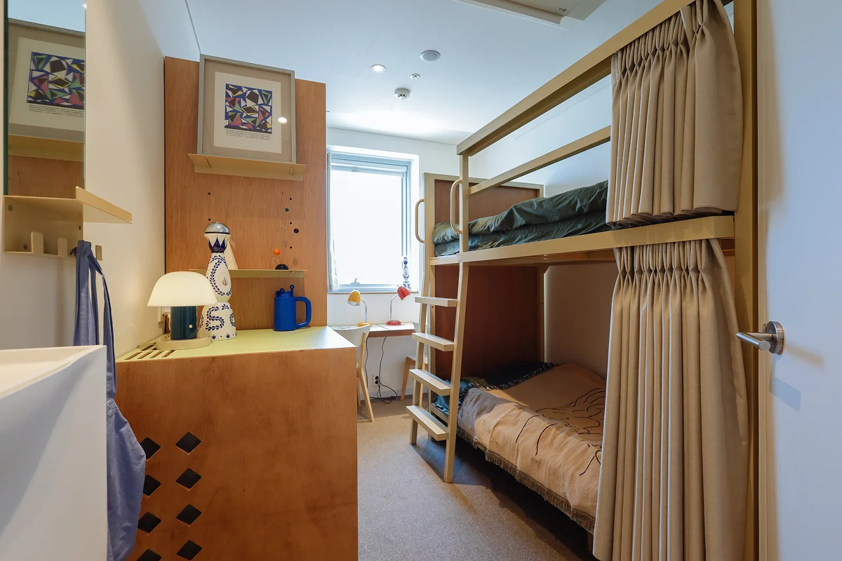 맹그로브 동대문 장기 숙박 Bunk 객실 전경 – 2층 침대와 개인 커튼이 설치된 코리빙 전용 객실로, 장기 체류 고객이 합리적인 가격에 편안하게 생활할 수 있는 공간. 창가에는 작은 테이블과 조명이 있어 업무나 식사를 위한 활용이 가능하며, 맹그로브만의 따뜻한 인테리어가 특징.