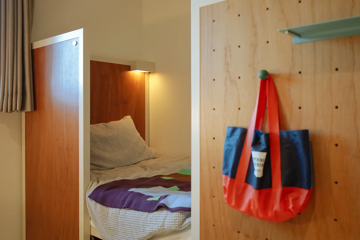 맹그로브 신설 장기 숙박 Twin Deluxe 룸 침실 – 따뜻한 우드톤 인테리어의 아늑한 객실로, 개별 침대와 조명이 마련되어 장기 체류 고객이 편안히 휴식할 수 있는 코리빙 공간.