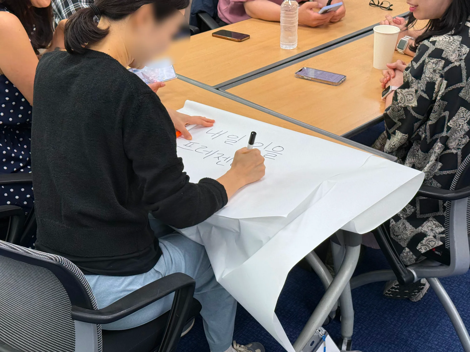 리더십 워크샵에 참여한 아이코닉스 직책자 중 한 명이 유성매직을 들고 전지 위에 토의 내용을 큰 글씨로 적고 있다.