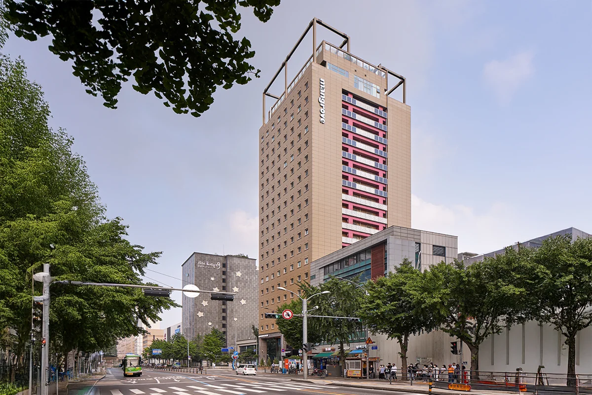 맹그로브 신설 장기 숙박 건물 외부 전경 – 대로변에 위치한 고층 건물로, 신설동 중심가에서 장기 체류 고객이 생활과 워케이션을 함께 누릴 수 있는 코리빙 숙소.