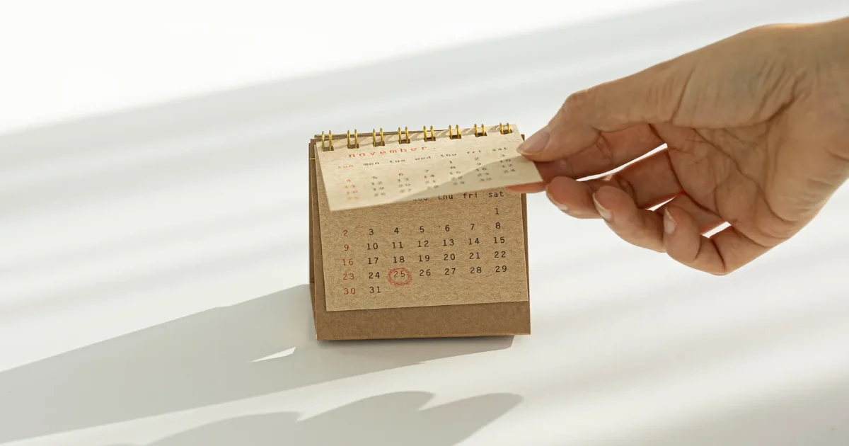 탁상 달력을 넘기는 손 촬영 일정 관리와 모델 섭외 시기
