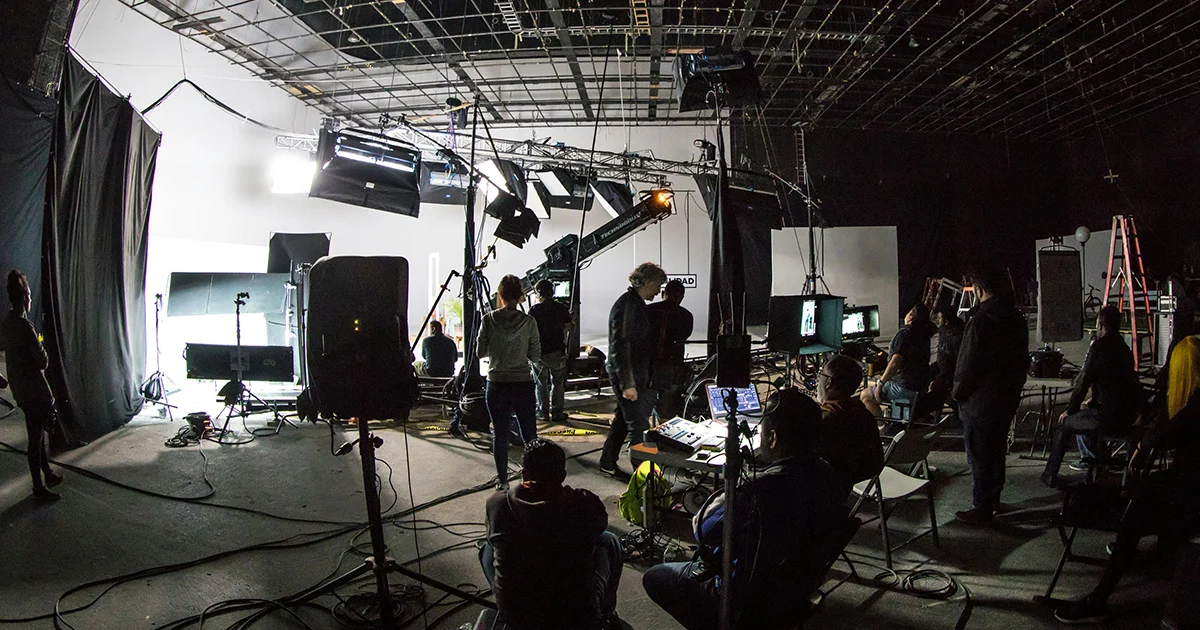 모델과 스태프들이 조명 아래에서 광고 촬영을 준비 중인 스튜디오 현장 전경.