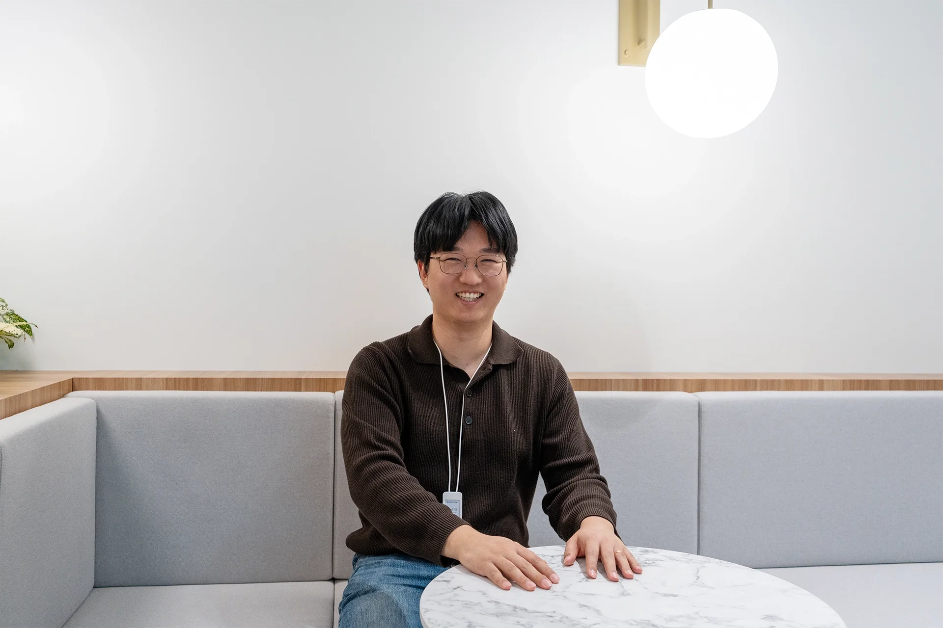   다우오피스HR 마케터 최광래 선임이 의자에 앉아 테이블에 손을 올려놓고 웃고 있는 모습