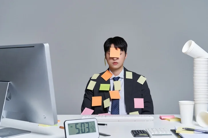 직장인이 의자에 앉아 있고 포스트잇이 얼굴과 옷에 붙어 있는 모습