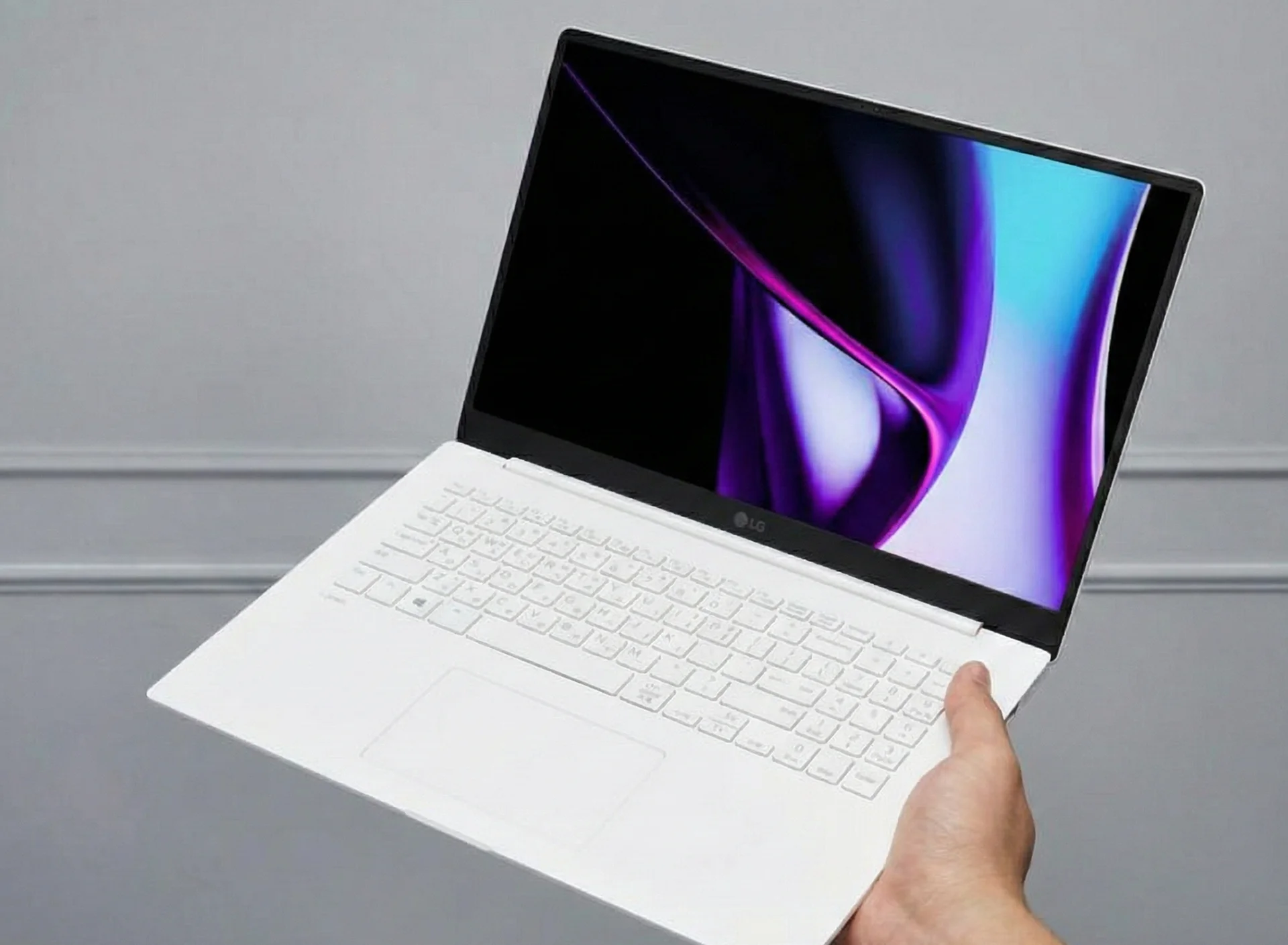 검정 베젤과 화이트 색상의 lg 그램 16 노트북이 열려있고, 한 손으로 노트북을 들고있는 모습