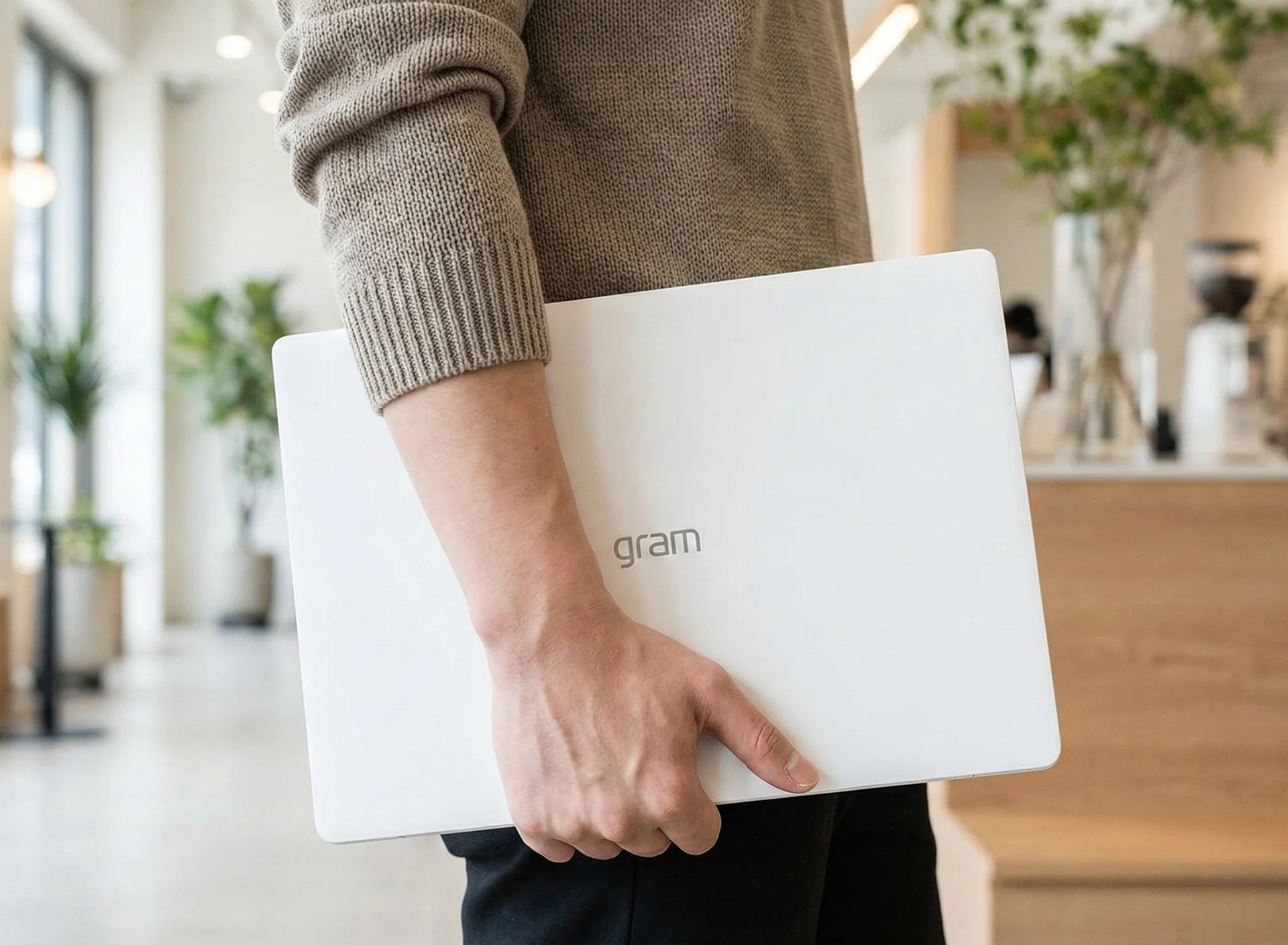 화이트 색상의 lg 루나 그램 노트북을 한 손으로 들고 카페로 외근을 나온 크리에이터의 모습