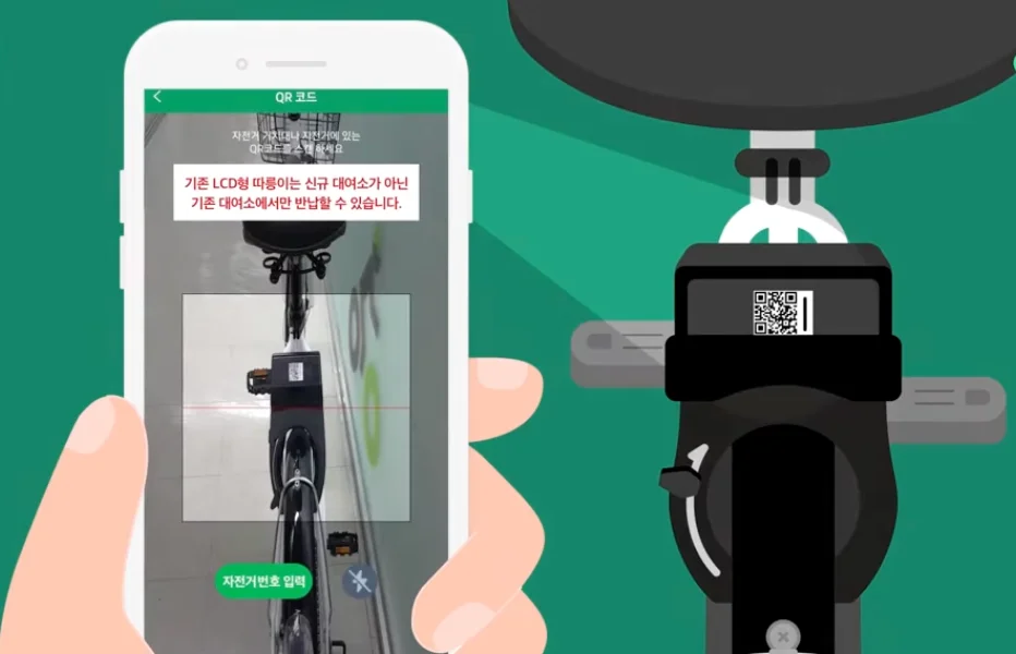 A hand holding a smartphone to scan a QR code located under the seat of a Seoul public bike.