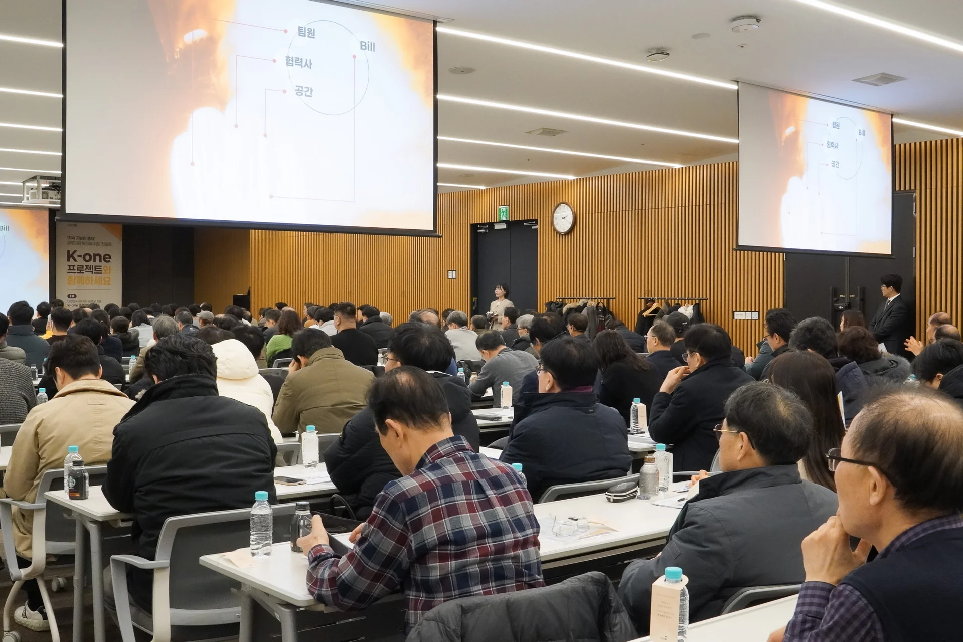 51층 대회의실 안, 설명회 진행 중 뒤편에서 촬영한 현장사진. 스크린이 뒤편 좌측, 우측에 한개씩 있고 앞쪽 가운데에 하나 있으며 스크린에는 폭발하는 사진과 구조도가 송출되고 있다.