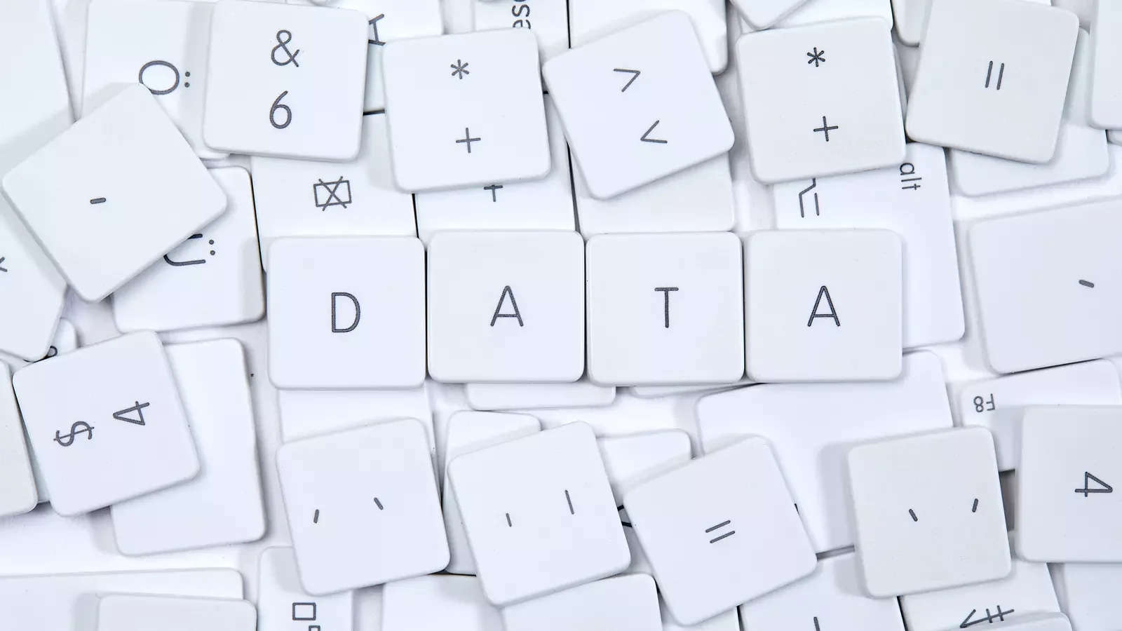 컴퓨터 키보드 키캡이 흩어져 있으며, 그중 ‘D’, ‘A’, ‘T’, ‘A’ 네 개의 키캡이 나란히 배열되어 ‘DATA’라는 단어를 형성하는 모습