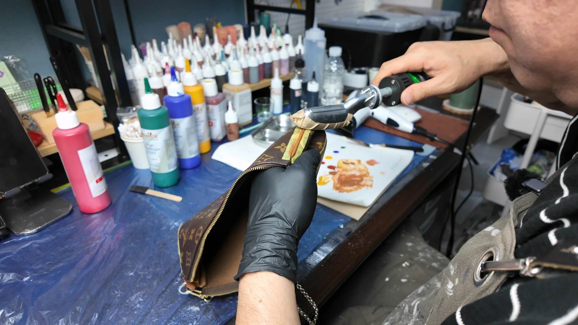 명품 파우치의 가죽 가장자리를 열처리 도구로 정밀하게 보정하는 수선 과정