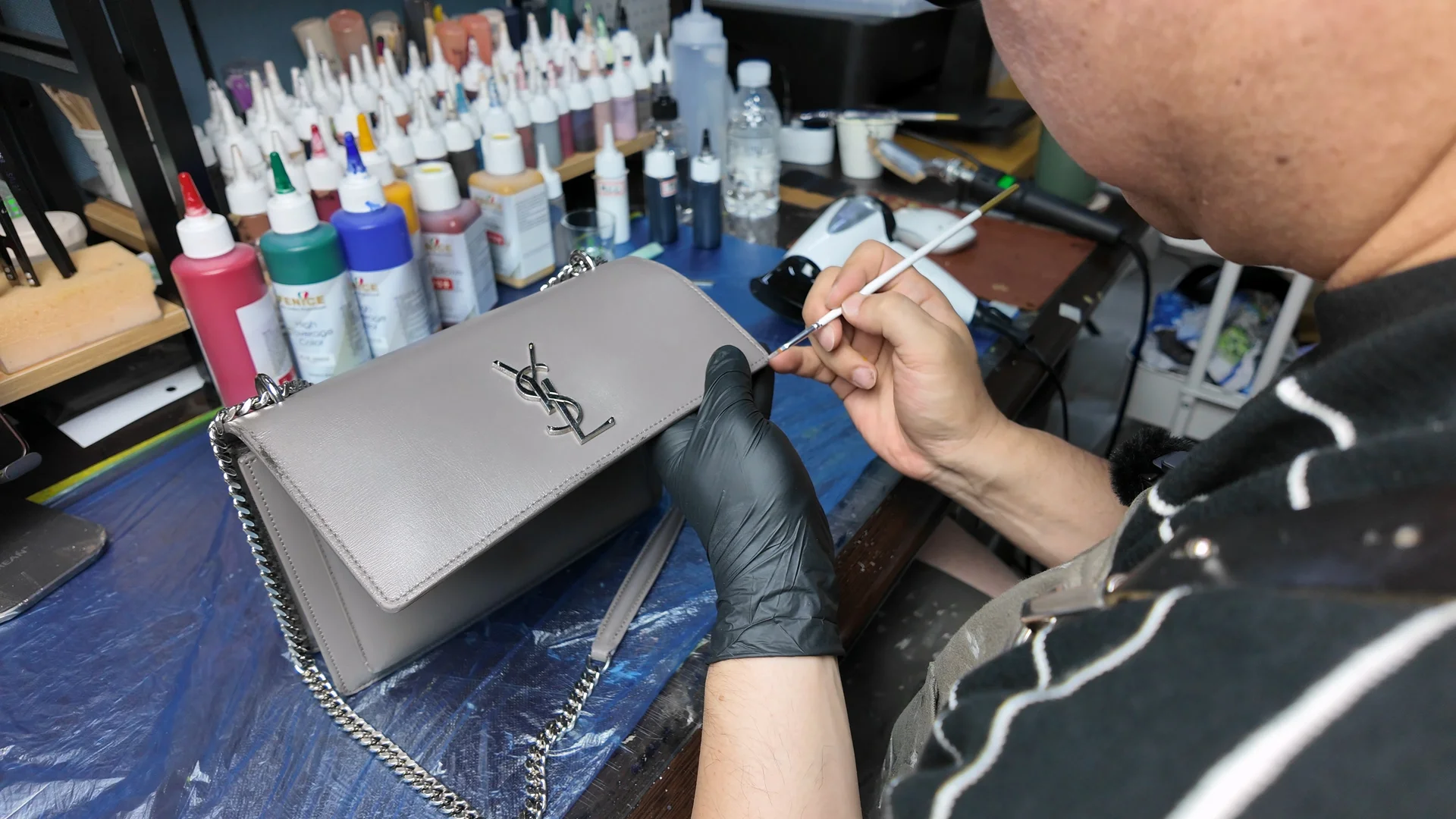 명품 가방 표면을 붓으로 보정하며 색감과 마감을 맞추는 수선 작업