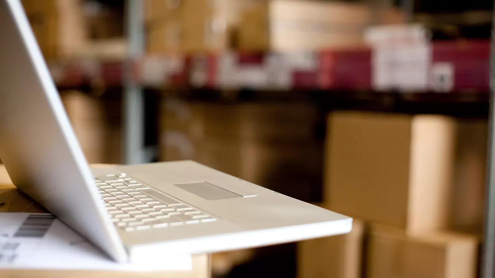 물류 창고 선반에 적재된 박스들 앞에서 노트북을 사용해 실시간 재고 현황을 확인하는 모습. 효율적인 창고 관리 시스템과 디지털 재고 관리 솔루션을 상징함