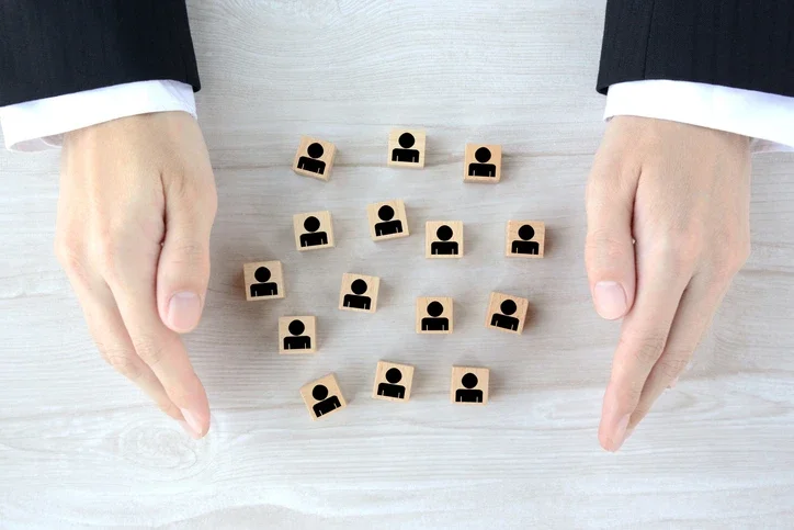 사람 상반신이 그려진 나무 조각 16개를 사람 손이 둘러싸고 있는 모습