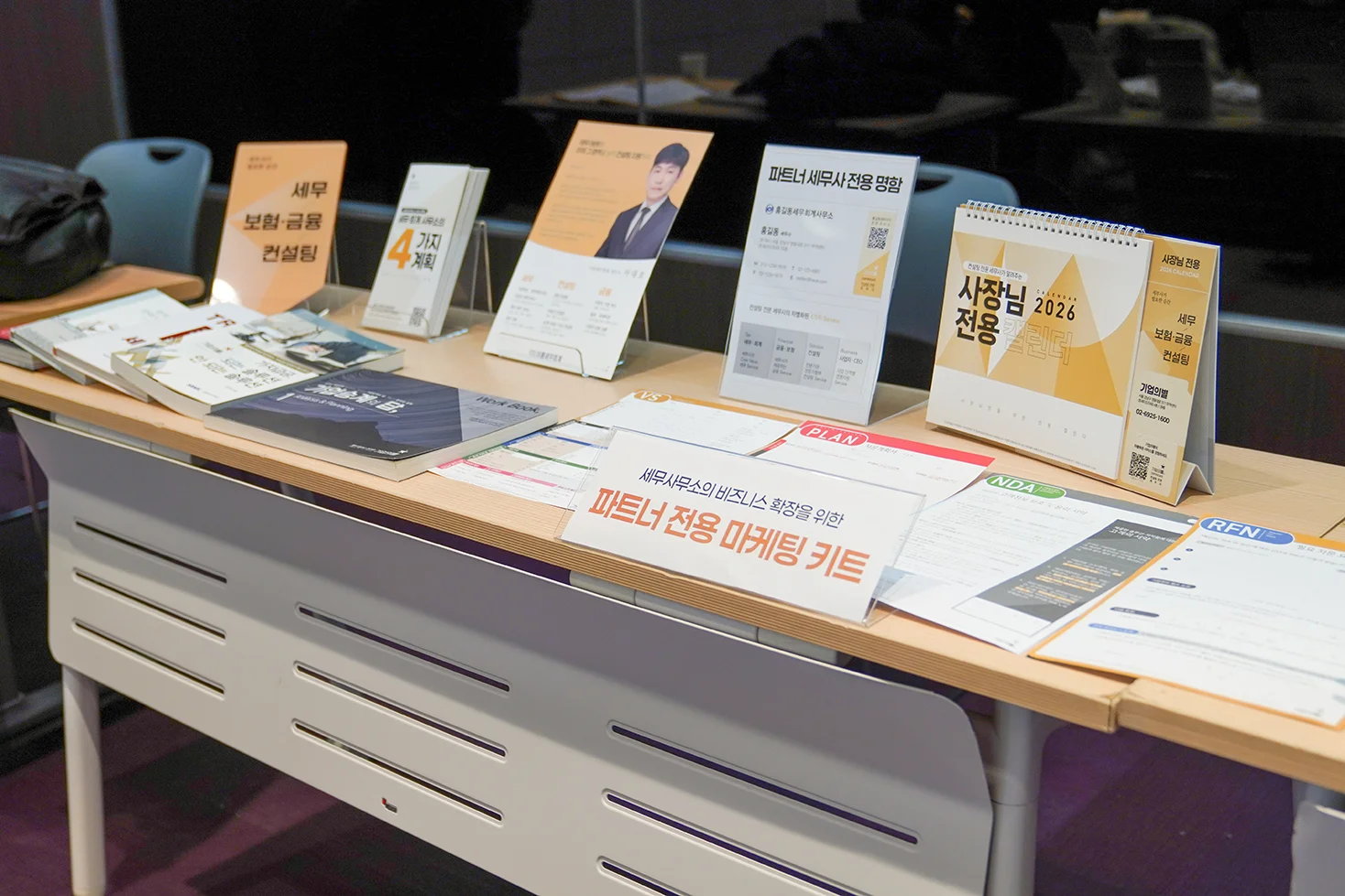 기업의별 부스 세팅 사진. 앞에 '파트너 전용 마케팅 키트' 아크릴 팻말이 있고 그 뒤로 기업의별이 제공하는 마케팅툴(표장,리플렛,캘린더등)과 기업의별 출간 서적, 컨설팅 자료가 비치되어있다.