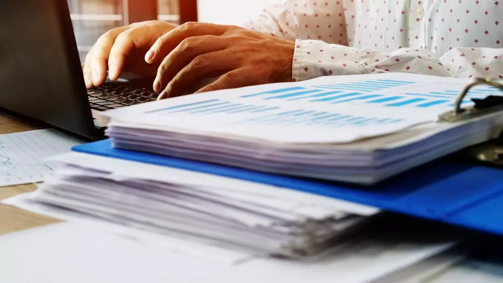 서류 뭉치와 노트북을 활용해 연말정산 지급명세서 신고 자료를 정리하는 인사 노무 관리 현장