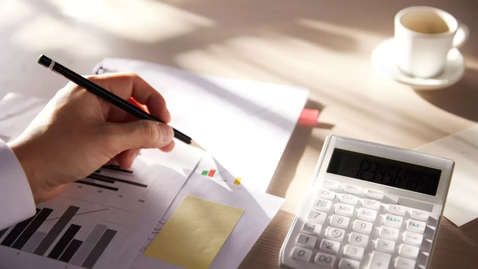 재무 차트와 그래프 분석, 손에 든 연필, 계산기, 커피 컵