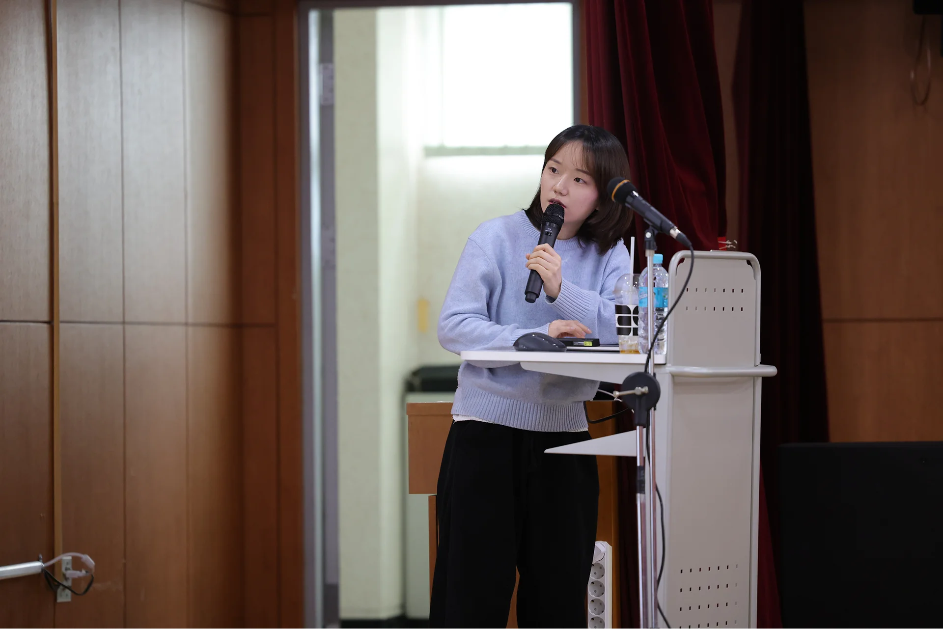2359 임정아 팀장님이 강단에서 마이크를 잡고 발표를 하고 있다.