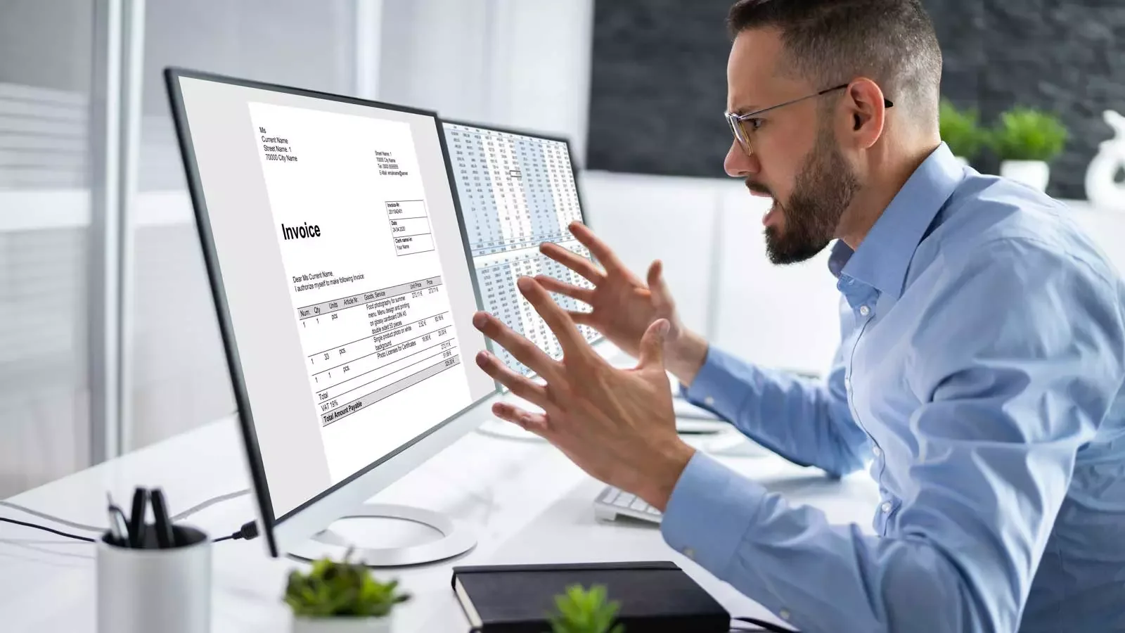 컴퓨터 모니터에 띄워진 인보이스와 상세한 회계 장부 데이터를 확인하던 남성이 예상치 못한 수치를 발견하고 양손을 벌리며 당황해하는 사무실 내부 전경