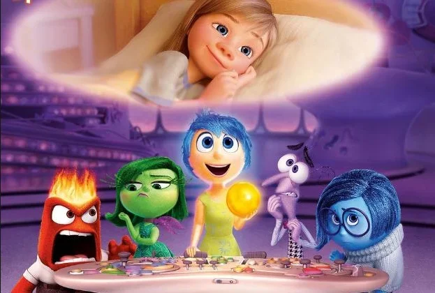 Scene from Pixar’s Inside Out showing Joy, Sadness, Anger, Disgust, and Fear gathered at the control panel inside Riley’s mind while Riley lies in bed above, smiling as she imagines a happy memory.