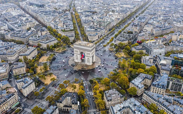 Aerial photograph of Paris, showing the Arc de Triomphe at the center of a radial city layout with broad boulevards extending outward, illustrating the planned urban structure of the city.